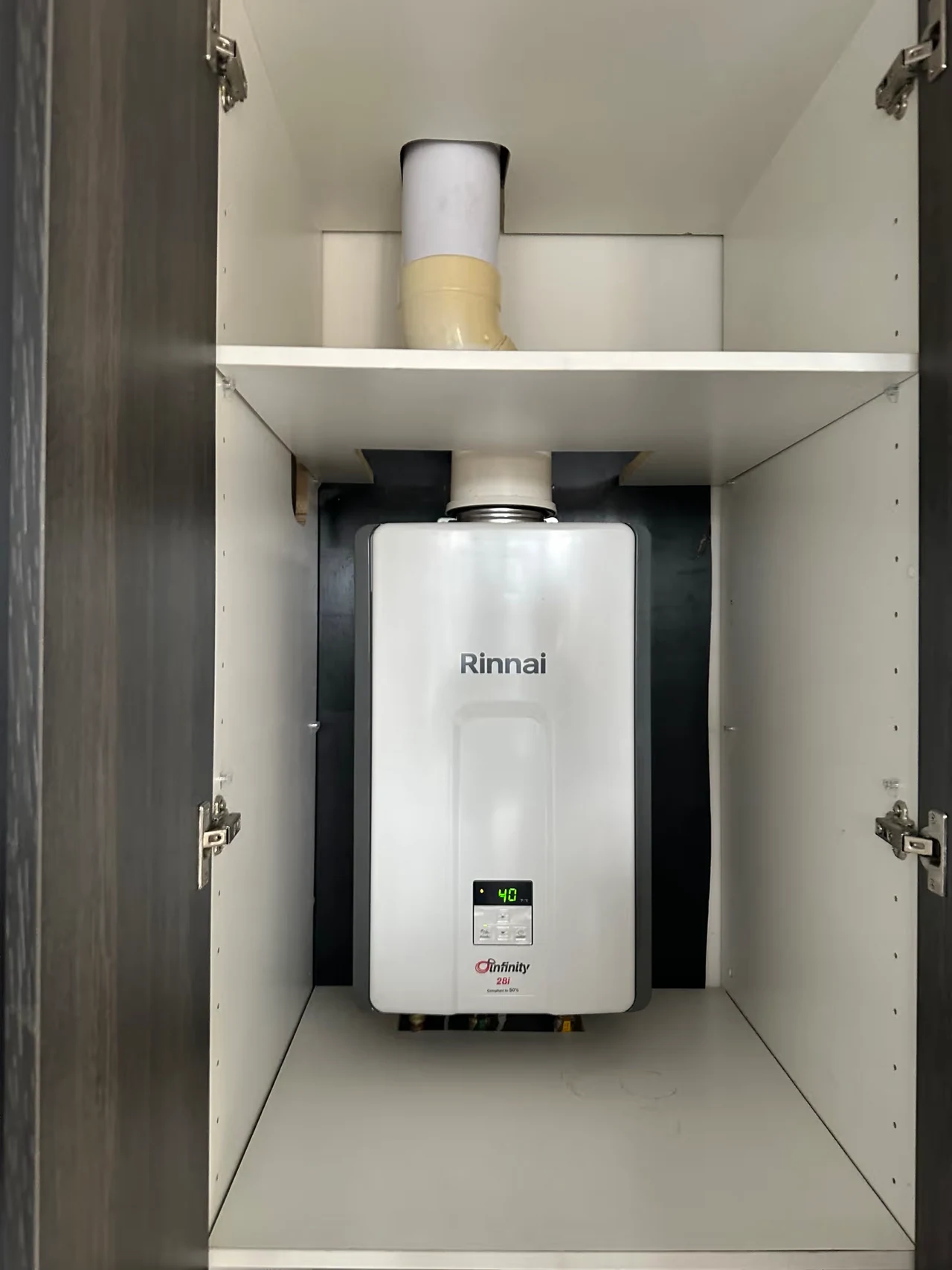 Indoor continuous-flow hot-water unit with its original labels and connections